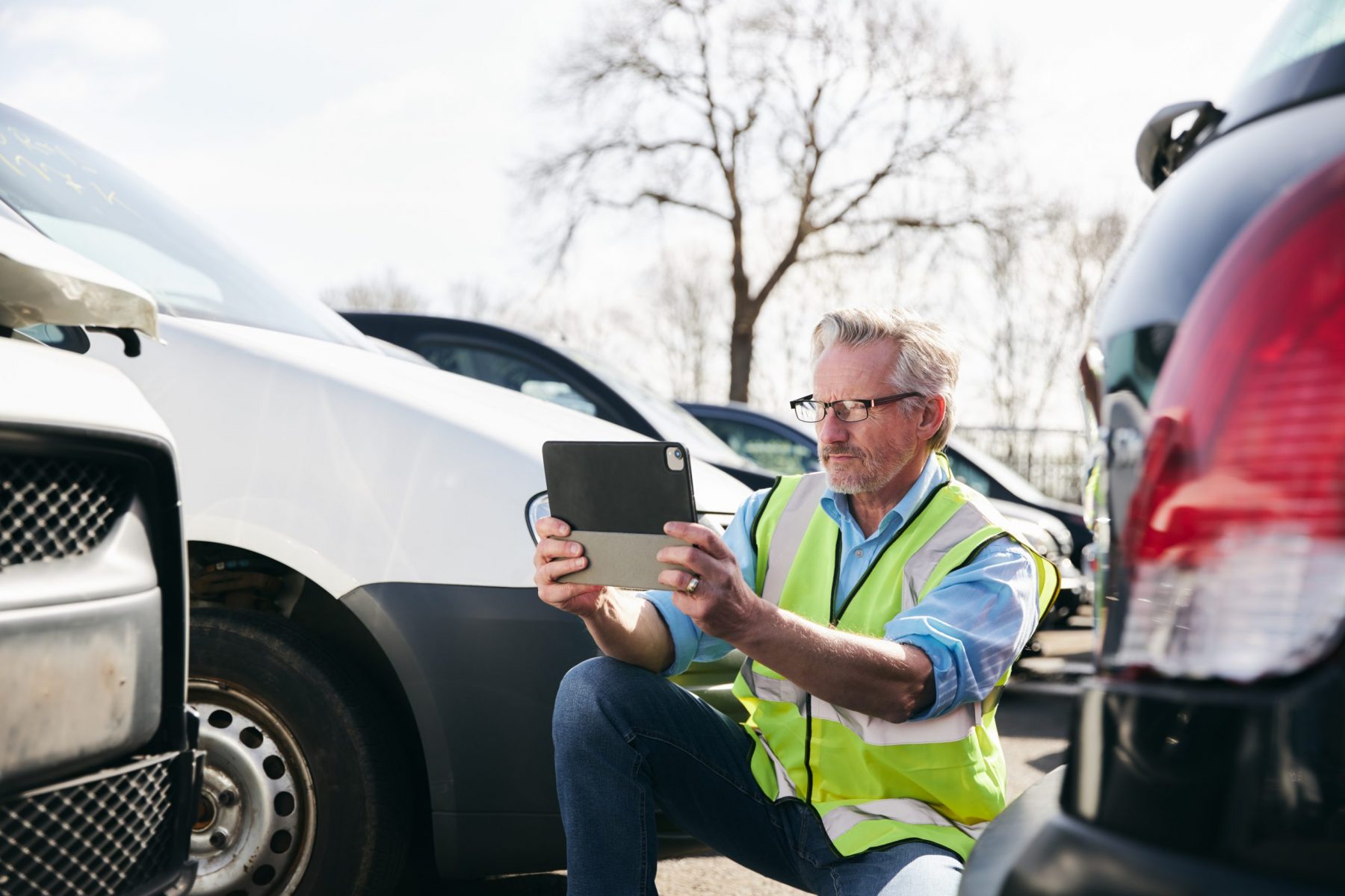 Man in neon green vest assessing damage of car