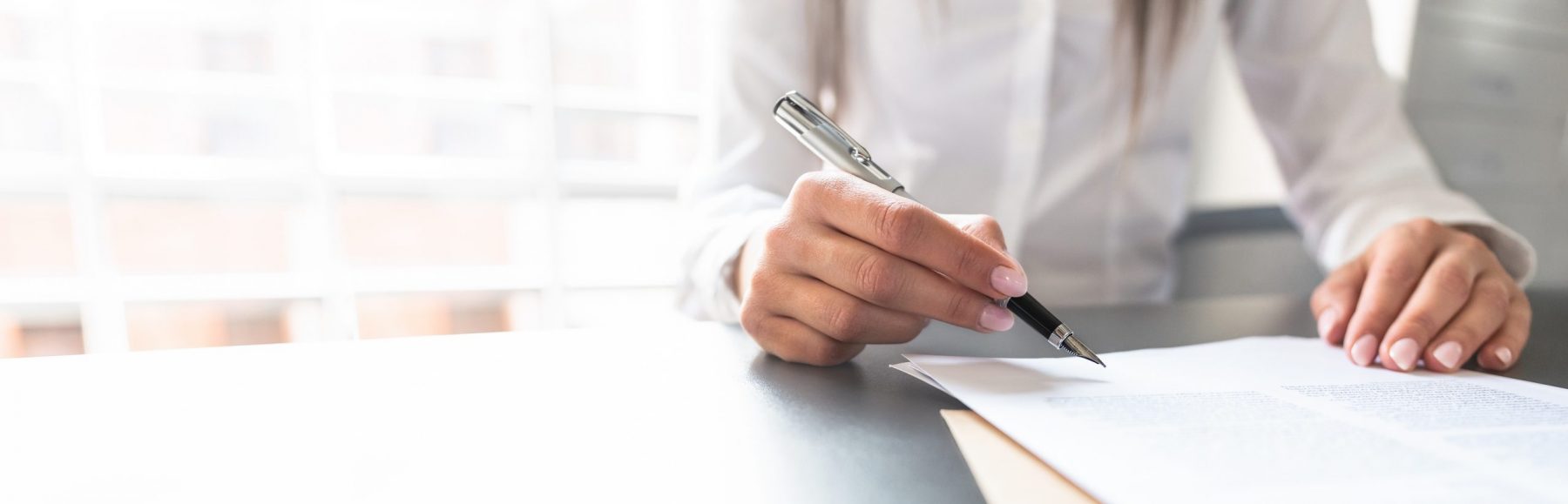 Business woman signing contract document on office desk.
