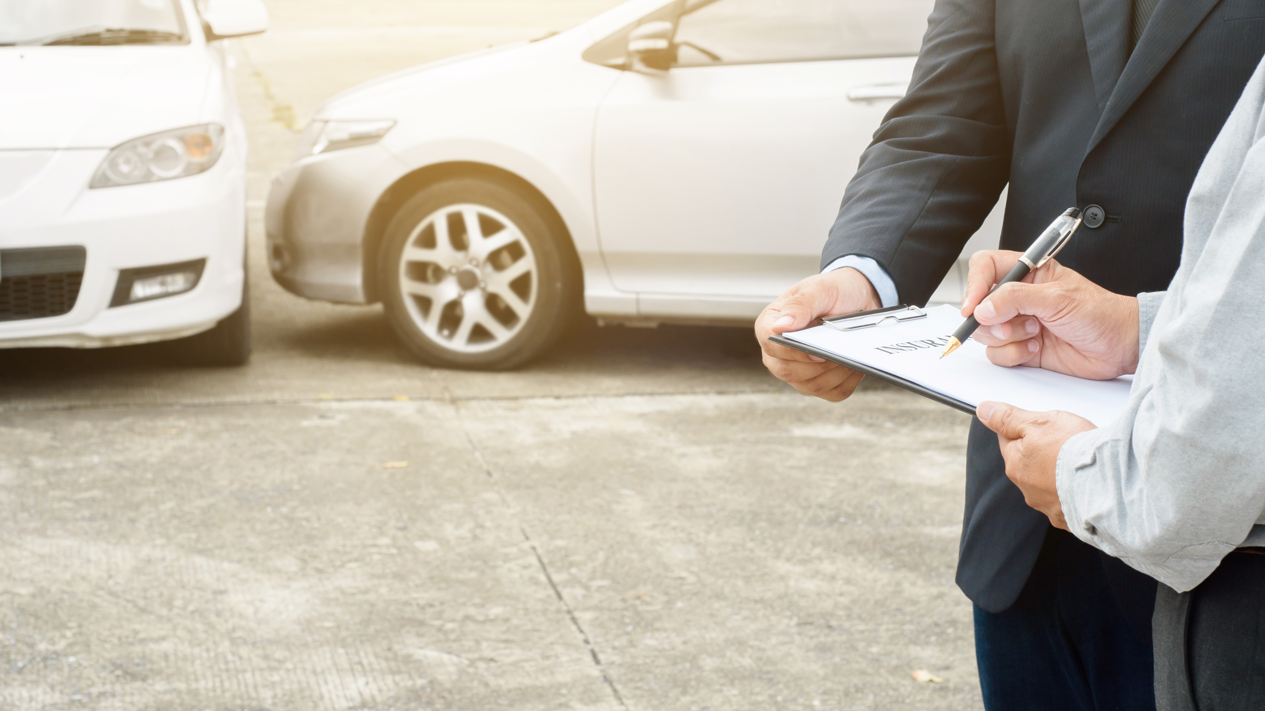 No-fault insurance agent claim process after car crash Two men stand holding papers in front of two vehicles that have been in a car accident to file no-fault insurance claim