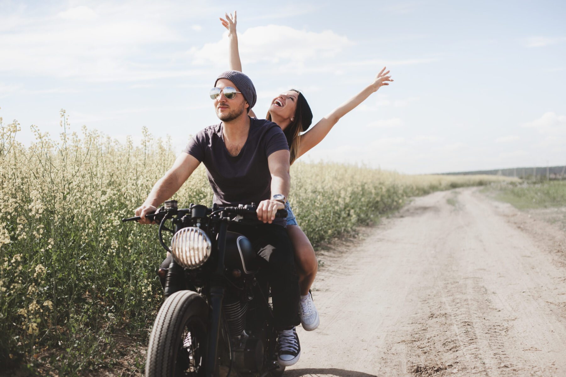 Couple in a field on a motorcycle.