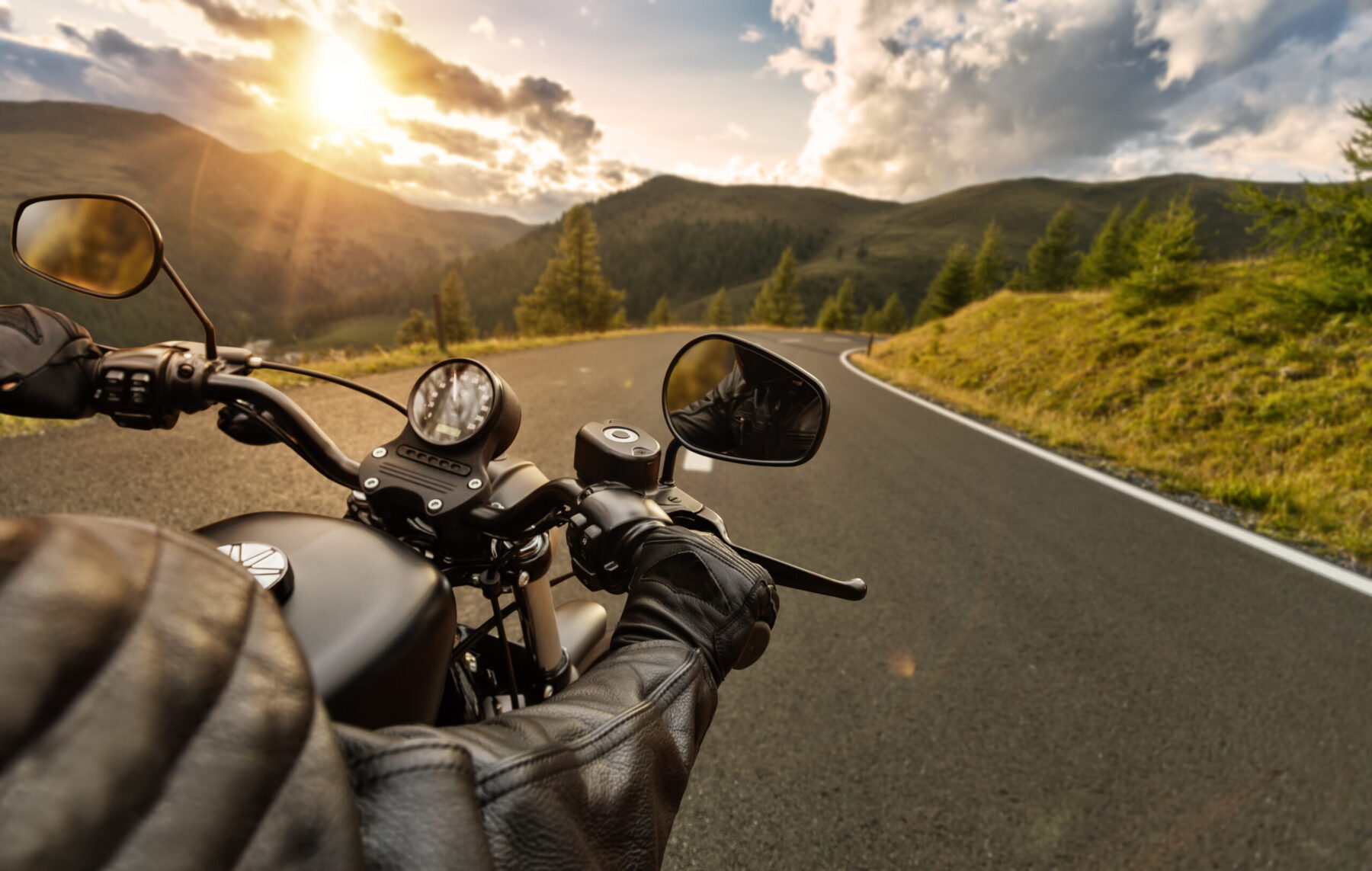 Motorbiker holding steering bar, riding in beautiful sunset dramatic sky