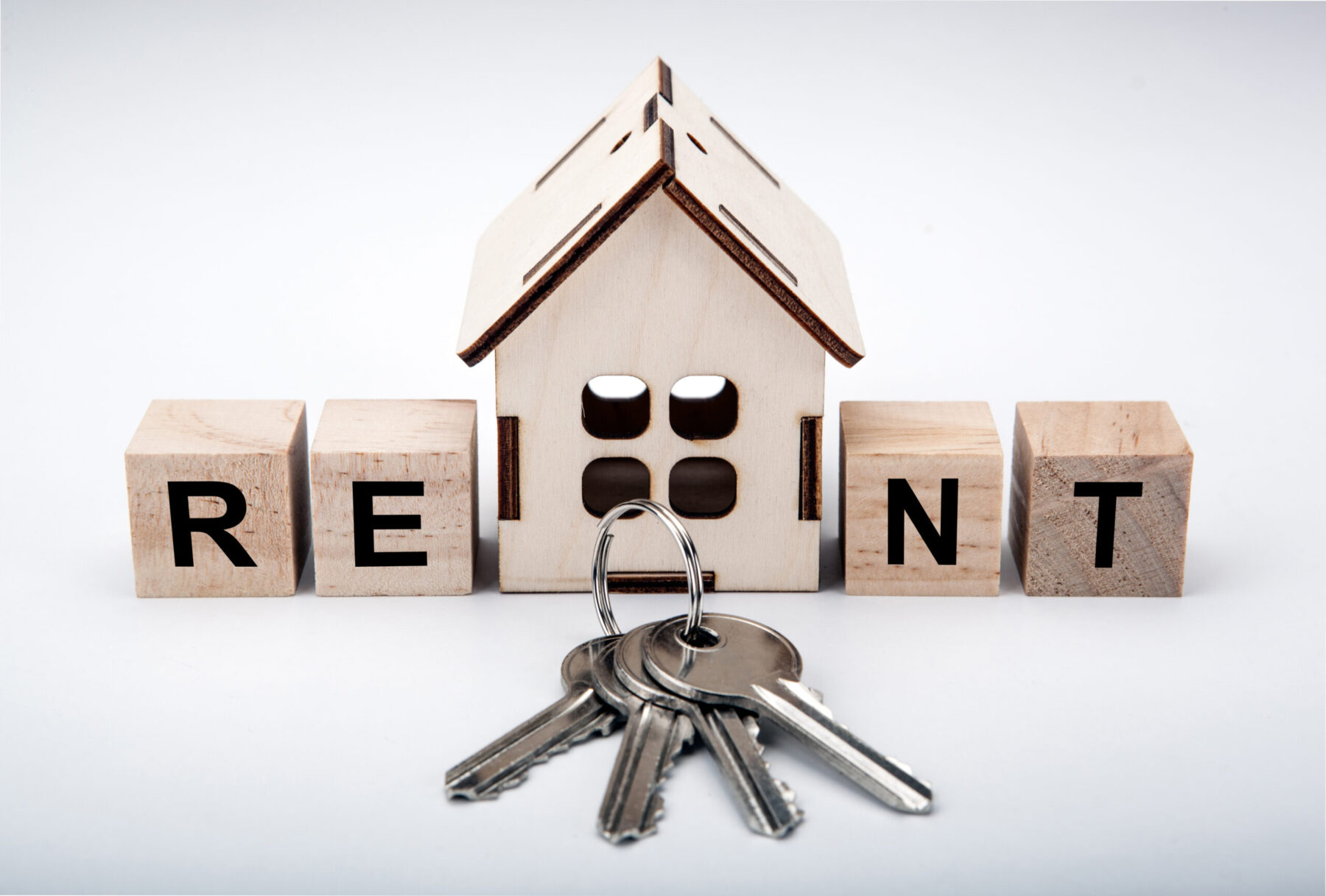 One miniature house with wooden cubes with inscription rent and door keys