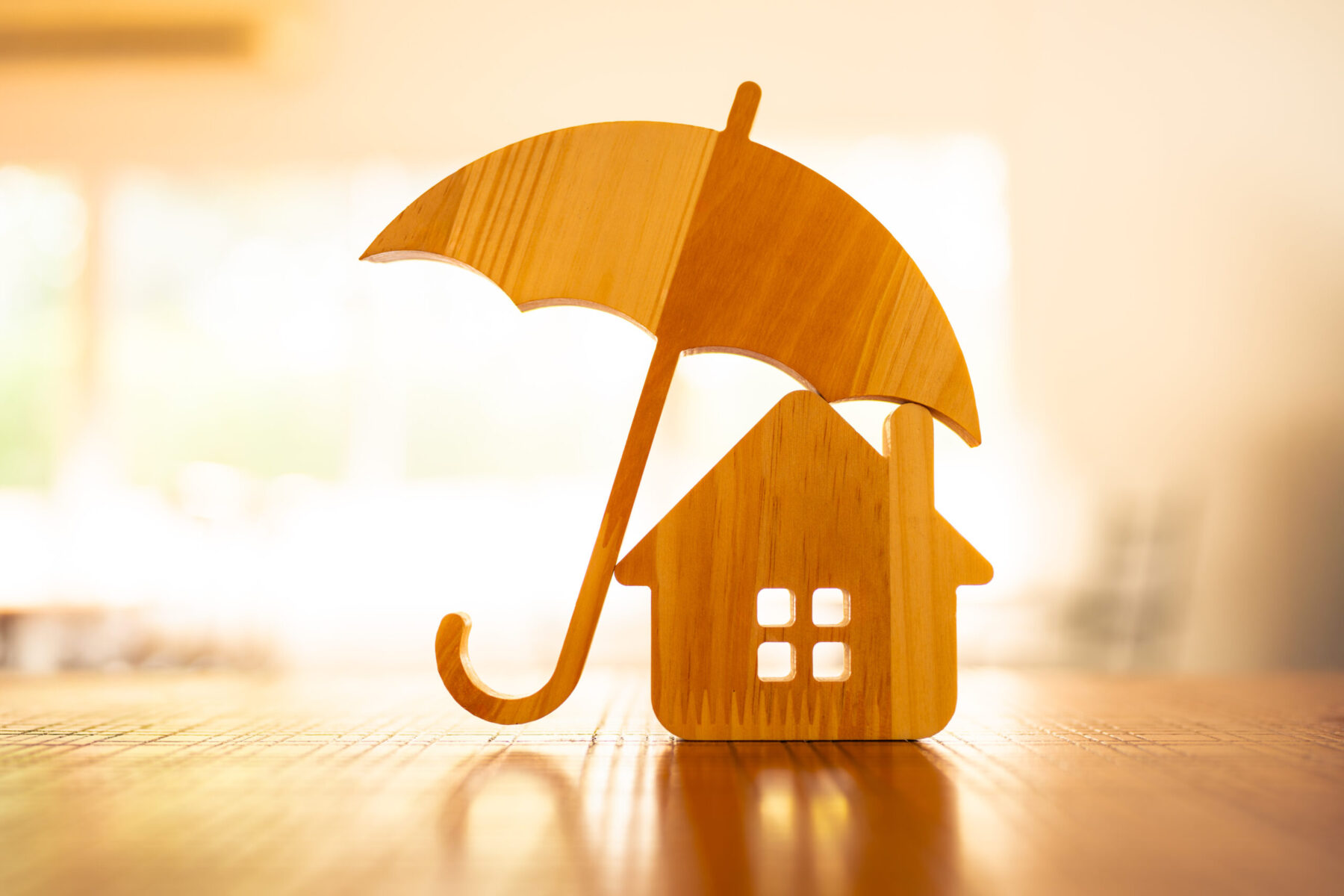 Model of umbrella with house on wooden table.