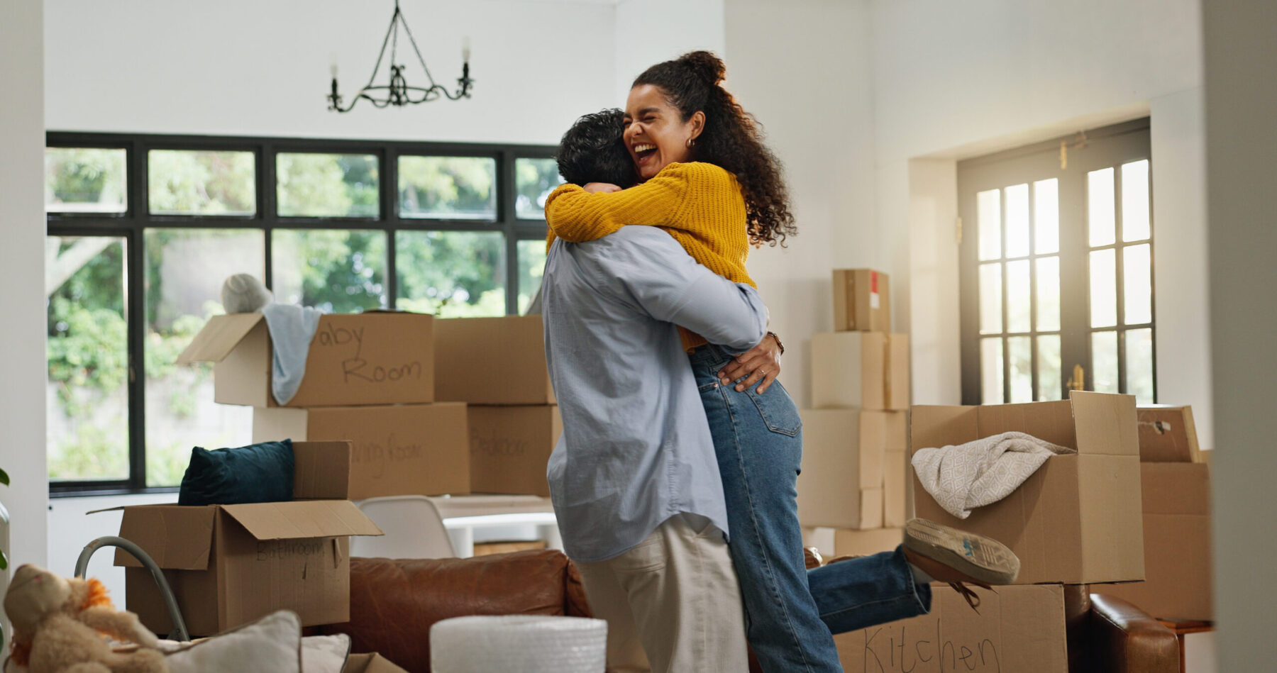 Wman and man hugging in living romm full of boxes.