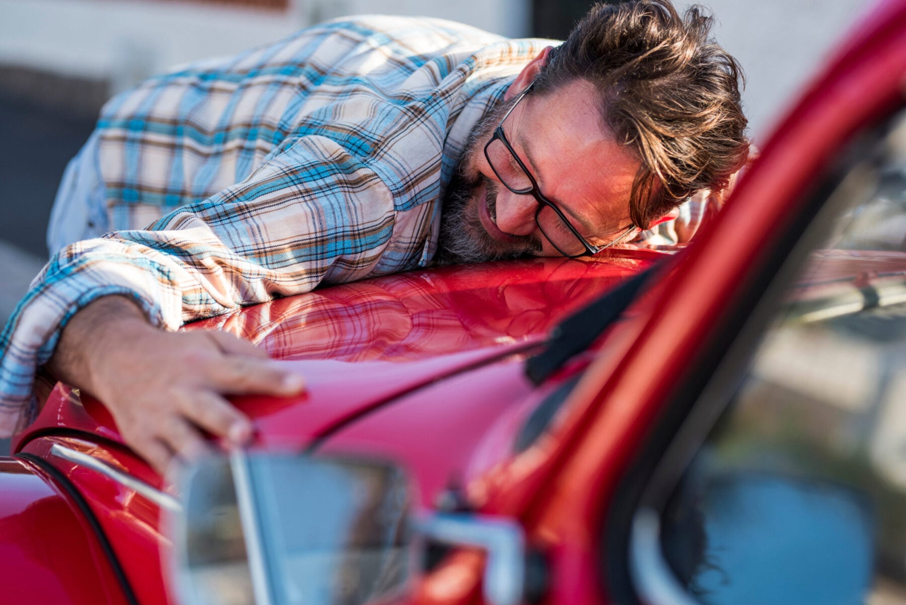 Bearded man is hugging his new car and smiling - love for auto vehicle.