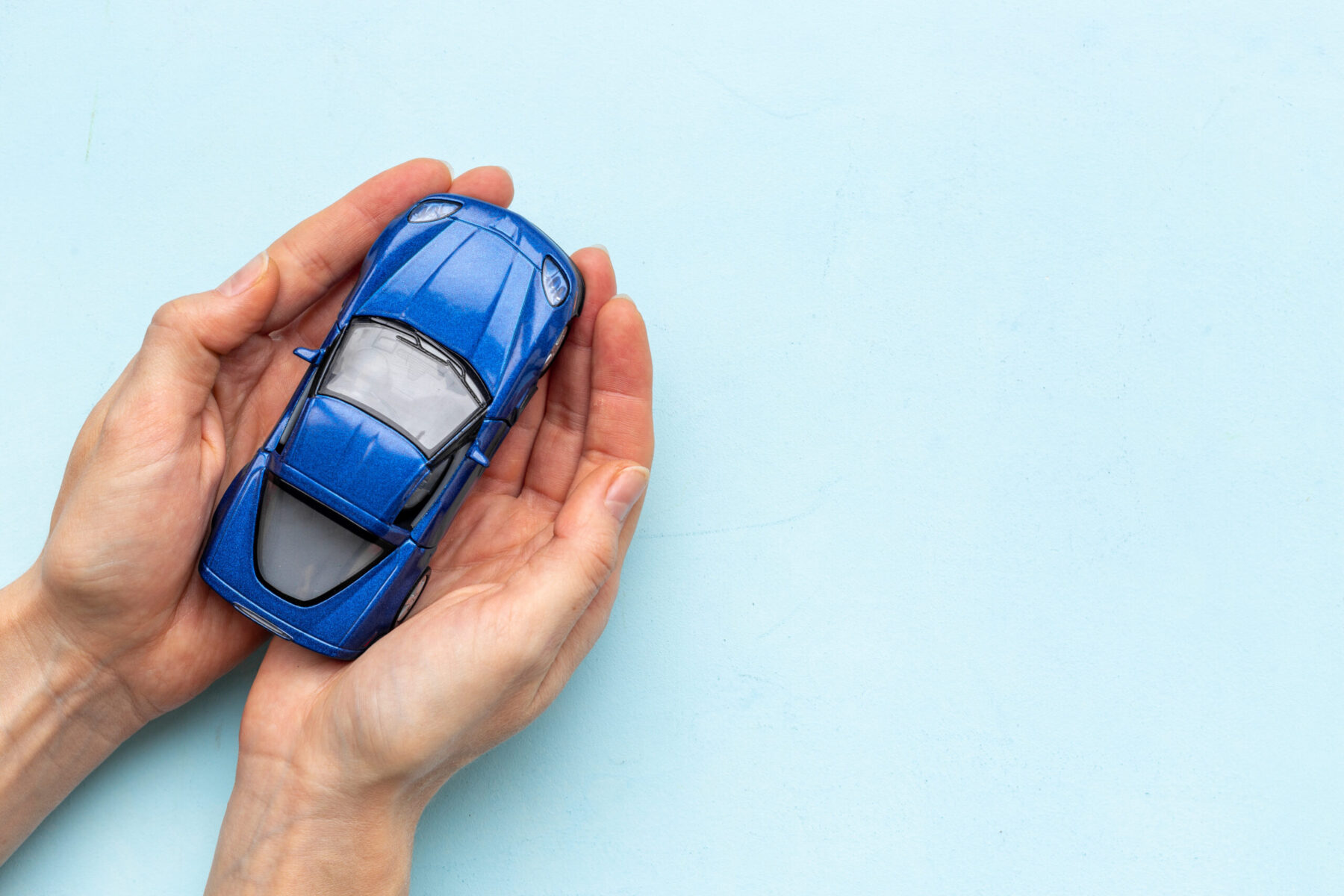 Toy car in hands, top view. Car insurance concept.