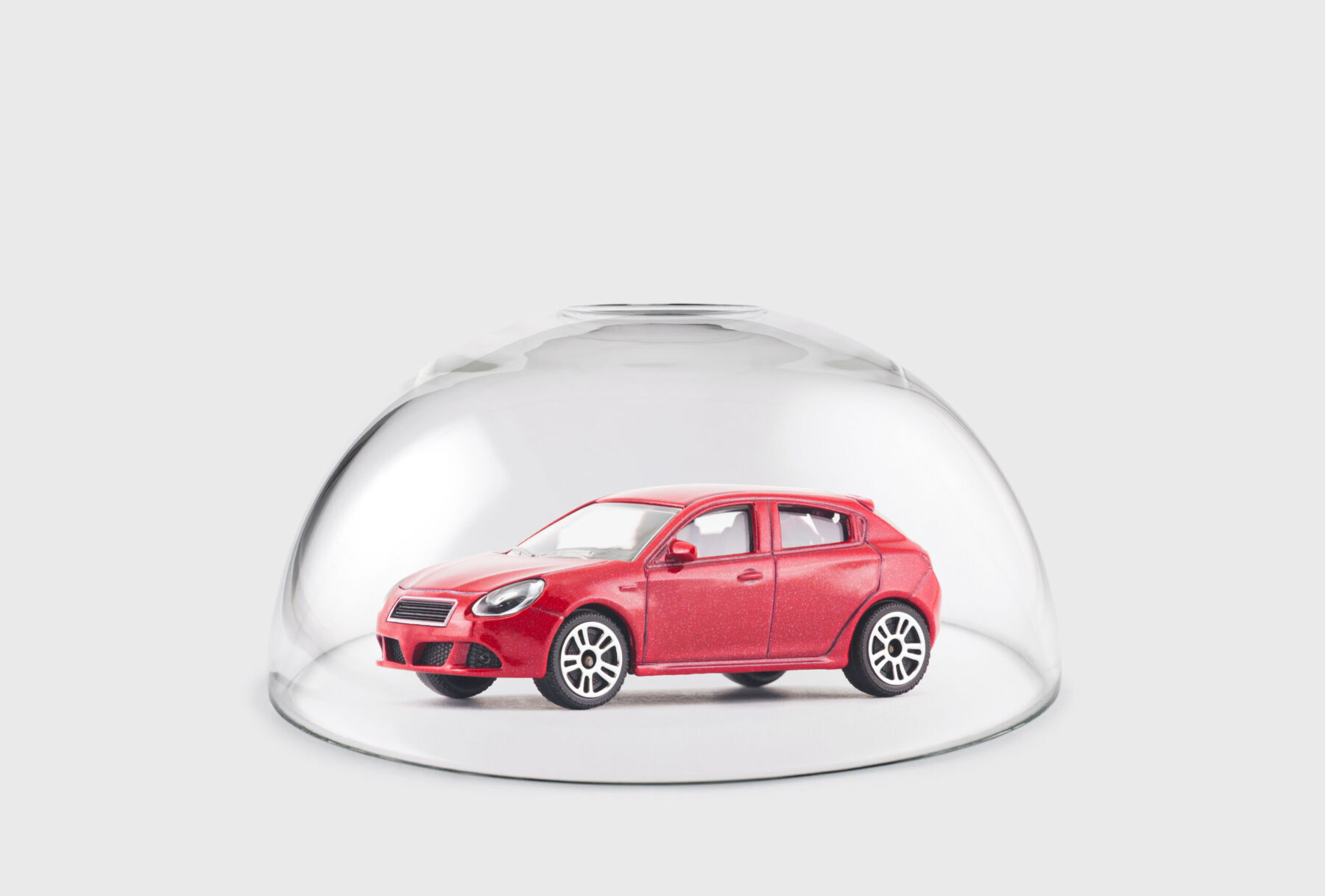 Red car protected under a glass dome.