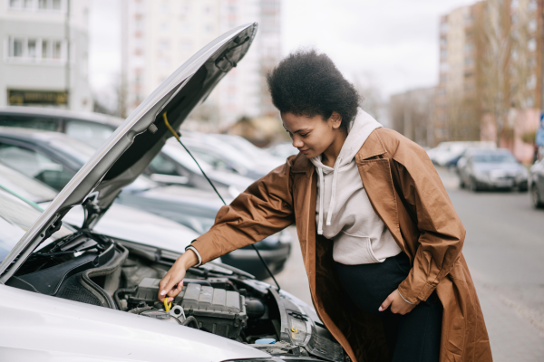 Woman checking car engine.