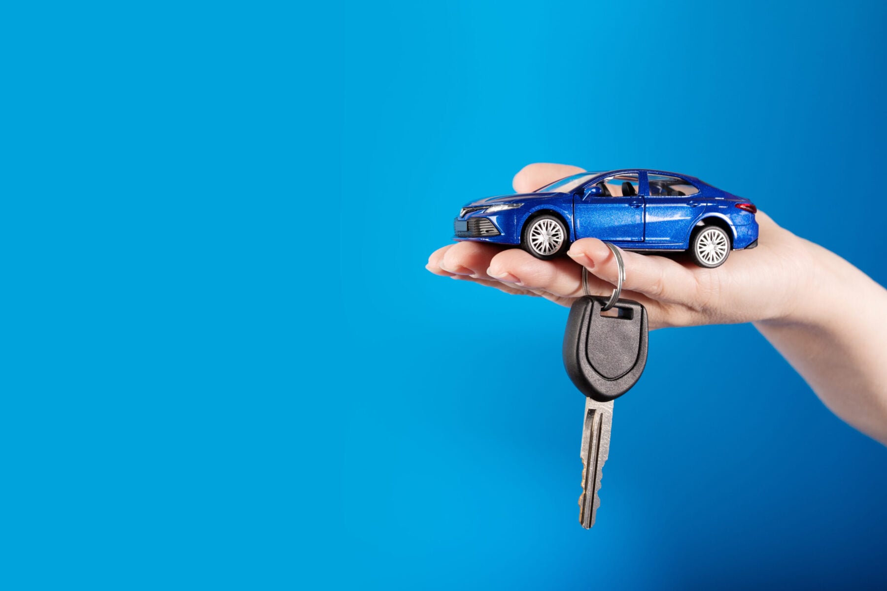 Person holding toy car in hand with keys.