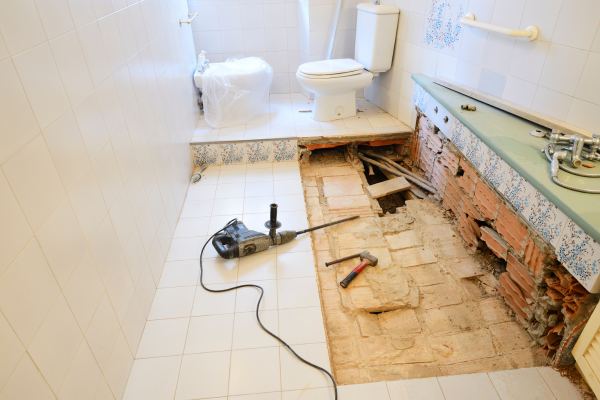 VIew of bathroom floor being removed with tools.