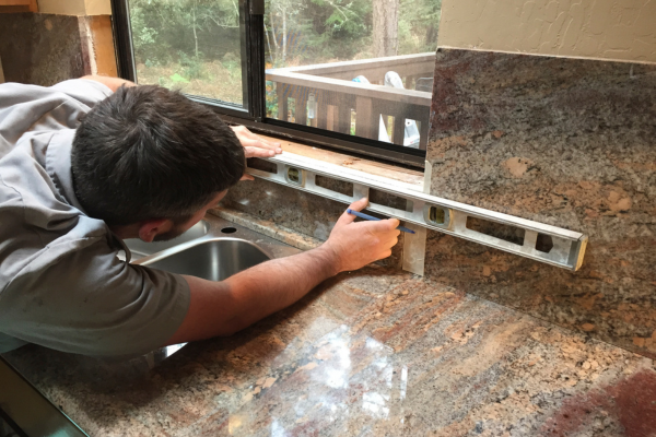 Man using leveler to measure countertops.